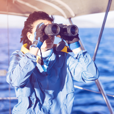 Femme observe la mer avec des jumelles bateau