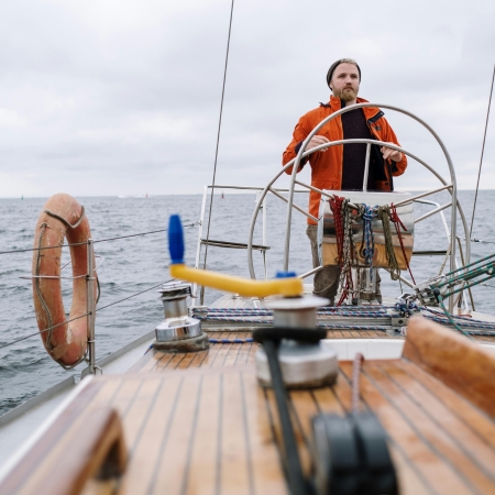 Navigateur à la barre de son bateau avec pont verni